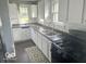 Well-lit kitchen with white cabinets, black countertops, and double basin sink offers a functional cooking space at 237 Ringwood Way, Anderson, IN 46013