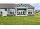 Exterior rear of home showcasing the covered patio, large windows, stone accents, and green lawn at 3544 Wrangler Dr, Bargersville, IN 46106