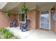 Welcoming brick front porch featuring rocking chairs, hanging plants and a storm door at 603 Ophelia Dr, Avon, IN 46123