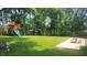 Spacious backyard featuring a wooden playset and a concrete patio set amongst mature trees at 6205 Bramshaw Rd, Indianapolis, IN 46220