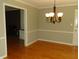 Open dining room shows hardwood flooring, an elegant chandelier, and entry to living room at 6205 Bramshaw Rd, Indianapolis, IN 46220