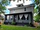 Charming two-story home featuring gray siding, a covered porch with white curtains and a colorful butterfly decoration at 2828 Robson St, Indianapolis, IN 46201