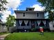 Two-story home showcasing gray siding, a covered porch with white curtains, and a lush green lawn under a blue sky at 2828 Robson St, Indianapolis, IN 46201