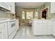 Sunlit eat-in kitchen boasts white cabinets, a breakfast nook, and tiled floors at 1612 S Jeanne Ct, New Palestine, IN 46163