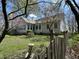 Backyard view showcasing a charming yard with mature trees, a small fence, and an elegant house design at 1612 S Jeanne Ct, New Palestine, IN 46163