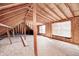 Unfinished attic space with exposed rafters, a window, and raw plywood flooring at 6502 Allisonville Rd, Indianapolis, IN 46220