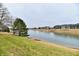 A grassy area with a lake view, a row of townhomes, and bare trees at 7854 Harbour Isle, Indianapolis, IN 46240