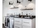Stylish wet bar featuring granite countertops, white cabinetry, open shelves and a beverage cooler at 10937 Pete Dye Rdg, Zionsville, IN 46077