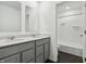 Bathroom with dual sinks, grey vanities, and a mirror, with view to tub and shower combo at 7856 Magnolia St, New Palestine, IN 46163