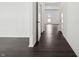 A hallway with dark hardwood floors leads to a door with a view of the outdoors at 7856 Magnolia St, New Palestine, IN 46163