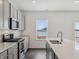 A well-lit kitchen features stainless steel appliances, a large island, and a window with a view of the outdoors at 7856 Magnolia St, New Palestine, IN 46163