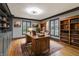 Bright home office showcasing hardwood floors, built-in bookshelves, natural light, and a large wooden desk at 6470 Around The Hills Rd, Indianapolis, IN 46226