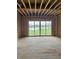 An unfinished living room featuring a large sliding glass door and exposed studs displaying construction progress at 1717 Beaufain St, Carmel, IN 46032