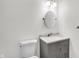 Small bathroom with gray vanity, oval mirror, and white toilet at 628 N Beville Ave, Indianapolis, IN 46201