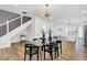 Modern glass dining table with black chairs, stylish chandelier, and open concept to kitchen at 628 N Beville Ave, Indianapolis, IN 46201