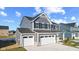 Two-story gray house with white garage doors and stone accents, viewed from the driveway side at 250 Mcnair Rd, Whiteland, IN 46184