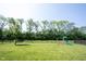 Spacious, green backyard with a swing set and surrounded by mature trees at 5573 Mahogany Dr, Noblesville, IN 46062