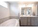 Bathroom featuring a soaking tub and a double vanity with gray cabinets and gold fixtures at 5573 Mahogany Dr, Noblesville, IN 46062