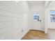 Bright entryway with white shiplap walls, light wood floors, and a view of the front door and other rooms at 10008 Sundley Dr, Indianapolis, IN 46239