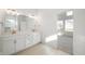 Bright bathroom features double vanity, white cabinets, and tiled shower, complemented by warm-toned flooring at 15846 Vitalize Run, Fishers, IN 46040