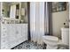 Bathroom with decorative tiled flooring, stylish vanity, elegant mirror, and patterned window curtain at 6906 Johnson Rd, Indianapolis, IN 46220