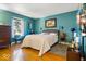 Bedroom featuring hardwood floors, teal walls, and natural light from the window at 6906 Johnson Rd, Indianapolis, IN 46220