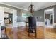 Formal dining room with hardwood floors, white wainscoting, modern light fixture, and view to kitchen at 6906 Johnson Rd, Indianapolis, IN 46220