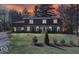 Dusk view of home with stone facade, well-lit windows, and manicured landscaping at 6906 Johnson Rd, Indianapolis, IN 46220