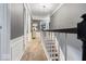 Hallway with staircase featuring a dark wood railing and carpeted steps leading to the upper level at 6906 Johnson Rd, Indianapolis, IN 46220