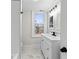 Bright bathroom featuring a white vanity, black fixtures, marble floors and a window with a neighborhood view at 1429 Brookside Pkwy N Dr, Indianapolis, IN 46201