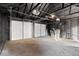 Spacious two-car garage interior, featuring painted black rafters and doors, and a concrete floor at 1429 Brookside Pkwy N Dr, Indianapolis, IN 46201