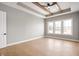 Empty bedroom with hardwood floors, tray ceiling, ceiling fan, and large windows at 1433 Chatham Hills Blvd, Westfield, IN 46074