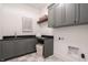 Functional laundry room features gray cabinets, ample counter space, and checkered flooring at 11896 Spring Mill Rd, Carmel, IN 46032