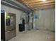 Unfinished basement with concrete walls, exposed pipes, and a stainless steel refrigerator at 12912 Broncos Dr, Fishers, IN 46037