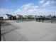 Community pool surrounded by paved area, black metal fence, and neighborhood homes at 12912 Broncos Dr, Fishers, IN 46037