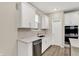 This kitchen features a stainless-steel dishwasher and sink, white cabinets, and light countertops at 18415 Depoe Ln, Westfield, IN 46074