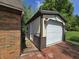 A detached garage with a white door, unique sconce lighting, and brick driveway at 6605 Donnelly Dr, Brownsburg, IN 46112