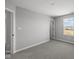 A gray room with carpet and a bright window looking out to a backyard, plus two doors and light switches at 4180 Bozeman Way, Bargersville, IN 46106