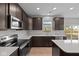 Modern kitchen featuring stainless steel appliances, dark wood cabinetry, white countertops, and a view of the backyard at 4186 Dutton Dr, Bargersville, IN 46106