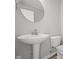 Clean powder room with a pedestal sink, round mirror, and white toilet at 4193 Bozeman Way, Bargersville, IN 46106