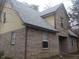 A detailed view of the side of the brick home showing yellow vinyl siding on the second level at 2021 N Graham Ave, Indianapolis, IN 46218
