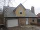 A view of the brick exterior with garage, chimney, and dormer with yellow siding at 2021 N Graham Ave, Indianapolis, IN 46218