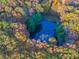 An aerial view of a serene pond surrounded by trees with vibrant fall colors, offering privacy and natural beauty at 7258 N Richardson Dr, Morgantown, IN 46160