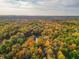 Expansive aerial shot showcasing vibrant fall foliage surrounding a tranquil pond nestled within a vast forest landscape at 7258 N Richardson Dr, Morgantown, IN 46160