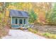 Charming small home exterior featuring a covered porch, surrounded by a vibrant forest and a serene pond at 7258 N Richardson Dr, Morgantown, IN 46160