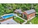 Aerial view of the backyard showcasing the pool, landscaped garden, and brick outbuildings with covered walkways at 2505 Riverside Dr, Columbus, IN 47201