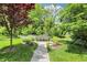 Stone walkway leading to a garden bench surrounded by lush greenery, trees, and flowers at 2505 Riverside Dr, Columbus, IN 47201