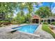 Outdoor swimming pool featuring a diving board and a pool house with an outdoor fireplace surrounded by trees at 2505 Riverside Dr, Columbus, IN 47201