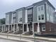 Newly constructed townhomes featuring brick and siding exteriors, white columns, and large windows at 2607 E New York St, Indianapolis, IN 46201