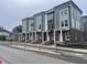 Modern townhomes feature stylish brick and siding facade, white pillars, and expansive windows at 2611 E New York St, Indianapolis, IN 46201